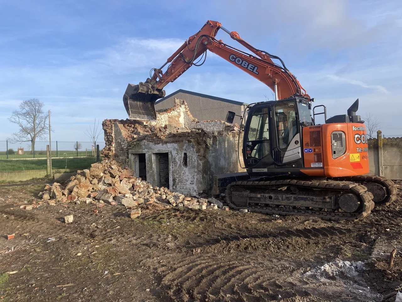 Démolition d'un bâtiment avec excavatrice orange